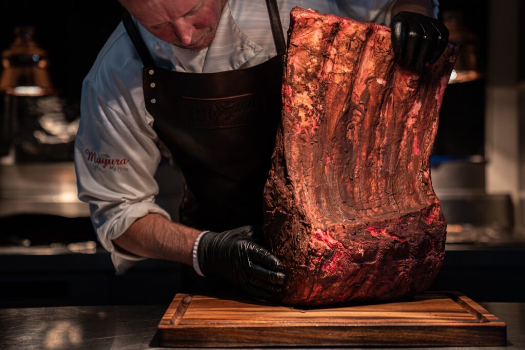 Chef holding a dry-aged Mayura Full-Blood Wagyu rib on a board