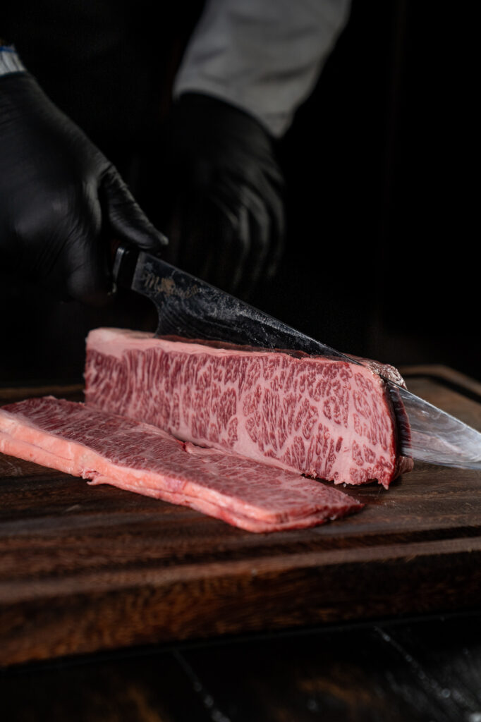 Knife slicing a Mayura Full-Blood Wagyu striploin revealing cross-section marbling