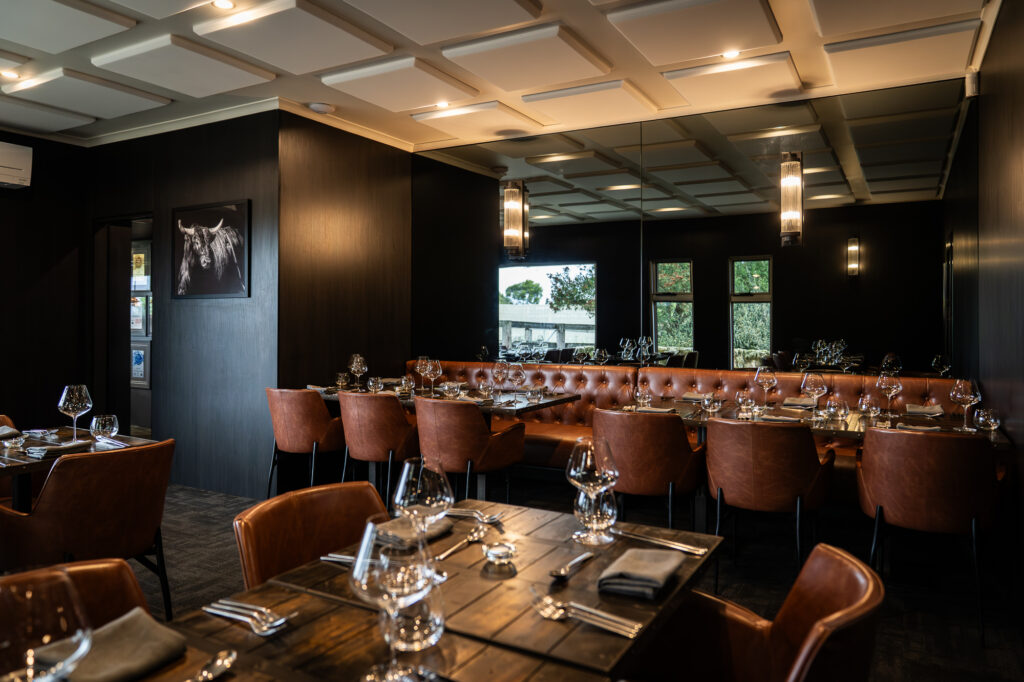The Mayura Wagyu Steakhouse main dining room, set for dinner with a bull portrait on the wall